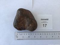 Photo of the large fire agate stone on a white background with ruler for scale showing approx. 8 cm size.