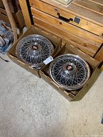 Two hubcaps side by side in cardboard boxes on concrete floor