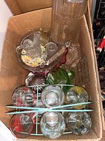 Top-down view of the box containing the glassware set, showing glasses in metal stand, bowls, and glass jars.