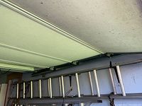 Aluminum extension ladder stored horizontally in garage, showing full length and mounting hooks.