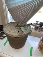 Angled front photo of the metal bread maker showing the full container and crank handle.