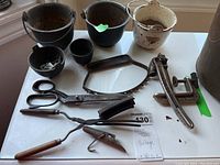 Image shows six metal pots of various sizes with visible rust and a collection of metal hand tools including a large pair of scissors and a clamp device.