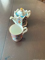 Hexagonal shaped Sadler teapot and matching mug showing detailed illustrations inspired by Elizabeth I Queen of England. Both pieces are decorated with colorful scenes and period designs.