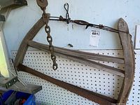 Photo showing two antique wood hand saws hanging on a pegboard wall, including wooden handle and frame construction.