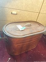 Side view of weathered metal tub with domed lid and top handle