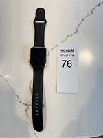 Front view of Apple Watch Series 2 showing black screen and black sport band with pin and tuck closure.