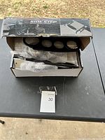 Opened box showing the side step parts including metal tubing and mounting brackets wrapped in bubble wrap inside a Bully branded box.