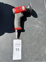 Red and black Chicago Pneumatic CP7202 pneumatic sander with rubberized grip and sanding pad, laid on dark surface.
