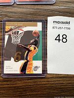 Photo of Kobe Bryant basketball card in protective case, showing front design with Kobe Bryant dunking and 'Points Per Game' text.