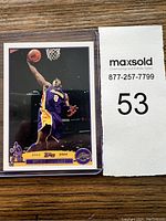 Front view of Kobe Bryant 2003-2004 Topps basketball card showing him mid-dunk, in protective sleeve