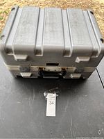 Closed metal case with reinforced ribbed design and carrying handle on top.