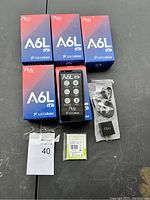 Lot showing five boxed Nuu Mobile A6L phones, one phone outside a box, sealed battery, charger, and USB cable.