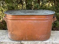Front view of the antique copper wash tub showing its oval shape and surface patina.