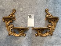 Overall pair of antique gold painted wall sconces showing symmetrical design and platforms for display or candles.