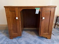 Front view of antique pine desk showing two paneled doors with white knobs and open kneehole