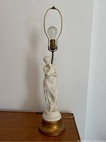Full view of antique porcelain lamp with brass base, showing the female figure and bulb socket.