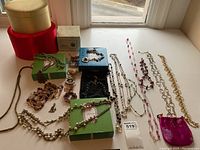 Overview of multiple costume jewelry pieces from Stella & Dot including various necklaces, bracelets, and earrings, with three jewelry boxes in red, green, and beige at a windowsill.