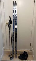 Complete set of skis, poles, and boots standing up against a door.