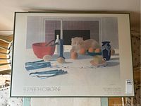 Framed exhibition poster showing detailed artwork with cat on dining table and asparagus.