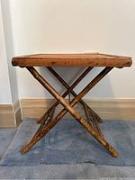 Side view of vintage bamboo folding table showing cross-legged structure and bamboo texture.