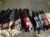 Full spread of men's ties laid out on bed, showing variety in colors and patterns.