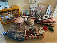 Widely scoped image showing the entire lot including button boxes, fabric bundles, pattern envelopes, and pincushions spread on carpet.