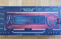 Display of the front of the Battle Crate packaging showing the 3-in-1 combo with detailed product images of keyboard, mouse, and headphones along with features and RGB lighting indications.