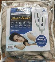 Front view of original packaging showing blanket label with a sleeping woman, features, size (queen), and dual control detail.