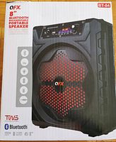 Front of QFX BT-84 speaker box showing image of the speaker with red LED lit grille, 8 inch driver, Bluetooth, FM radio, LED party lights, rechargeable.