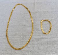 Necklace and bracelet displayed on white fabric.