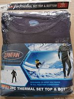 Top view of the folded thermal top in blue waffle knit texture inside original packaging with branding and size XXL.