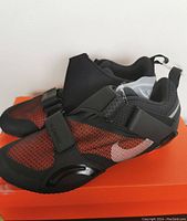 Side angled view of the black and red Nike M SuperRep Cycle shoes with white swoosh logo.