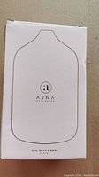 Front of box showing the AJNA Wellbeing logo, product silhouette line art, and product name 'Oil Diffuser Slate'.