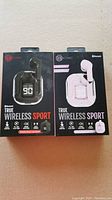 Photo of front side of two packaging boxes for Biconic True Wireless Sport ear buds in black and white colors with case images and product branding.