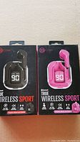 Front view of two unopened Biconic True Wireless Sport earbuds packs in black and pink colors showing charging cases with battery display and single earbuds.