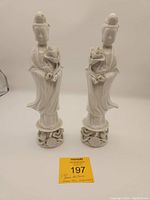 Two vintage Blanc de Chine Guan Yin porcelain figurines standing side by side, displaying their mirrored design and details.