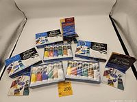 Three unopened boxed sets of Winsor & Newton Artisan water mixable oil colour beginner paint sets shown side by side with a yellow auction lot card visible