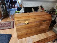 Closed view of a wooden chest showing its horizontal slatted curved lid, natural wood finish, and condition.
