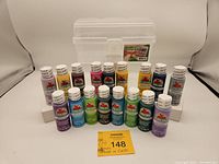Full set of 17 bottles of Apple Barrel acrylic paint arranged in three rows with clear carrying case behind.