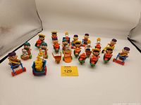 Wide view showing all 20 Peanuts 1989 McDonald's toys arranged in rows on white background with studio lighting. Characters sit on garden tools and accessories including lawn mowers, wheelbarrows, and carts.