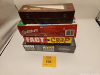 Stacked boxes of games Cranium (new unopened), Guesstures, Fact or Crap, and a brown box for Rummy game