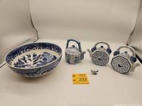 Photo of the full set showing the large blue and white Willow flow bowl, three porcelain teapots, and a small bird figurine.