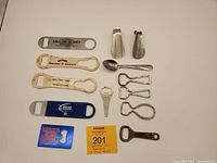 Full display of the vintage can openers and shoe horns lot showing variety of bottle openers and shoe horn tools on white background.