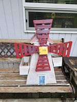 Front view of white painted wooden windmill with red blades and planter boxes on sides.