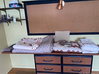 Photo showing all bedding items including quilts, sheet set, and pillowcases arranged on a wooden surface with drawers underneath.