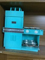 Front view of vintage blue Kenner Easy-Bake Oven with front door open and bakeware inside and on top.