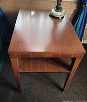 Single mid century mahogany end table showing top surface and tapered legs.