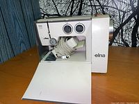 Front view of the Elna Lotus ZZ sewing machine with fold-down table and cord-wrapped foot pedal inside
