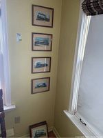Four of the eight framed and matted train prints hanging on a wall and stacked below, showing layout and style.