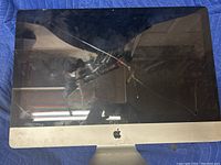 Front view of the Apple all-in-one computer showing multiple cracks on the display screen and wear marks on the aluminum frame.